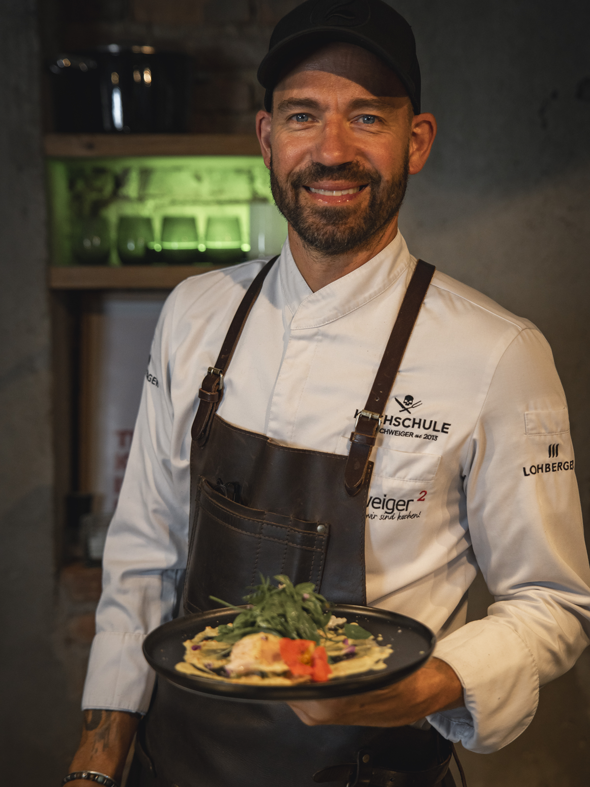 Profikoch Andi Schweiger mit einem fertigen Gericht in der Hand: Fisch Souse Vide | gebratener Blumenkohl | Curry Joghurt | Kräutersalat