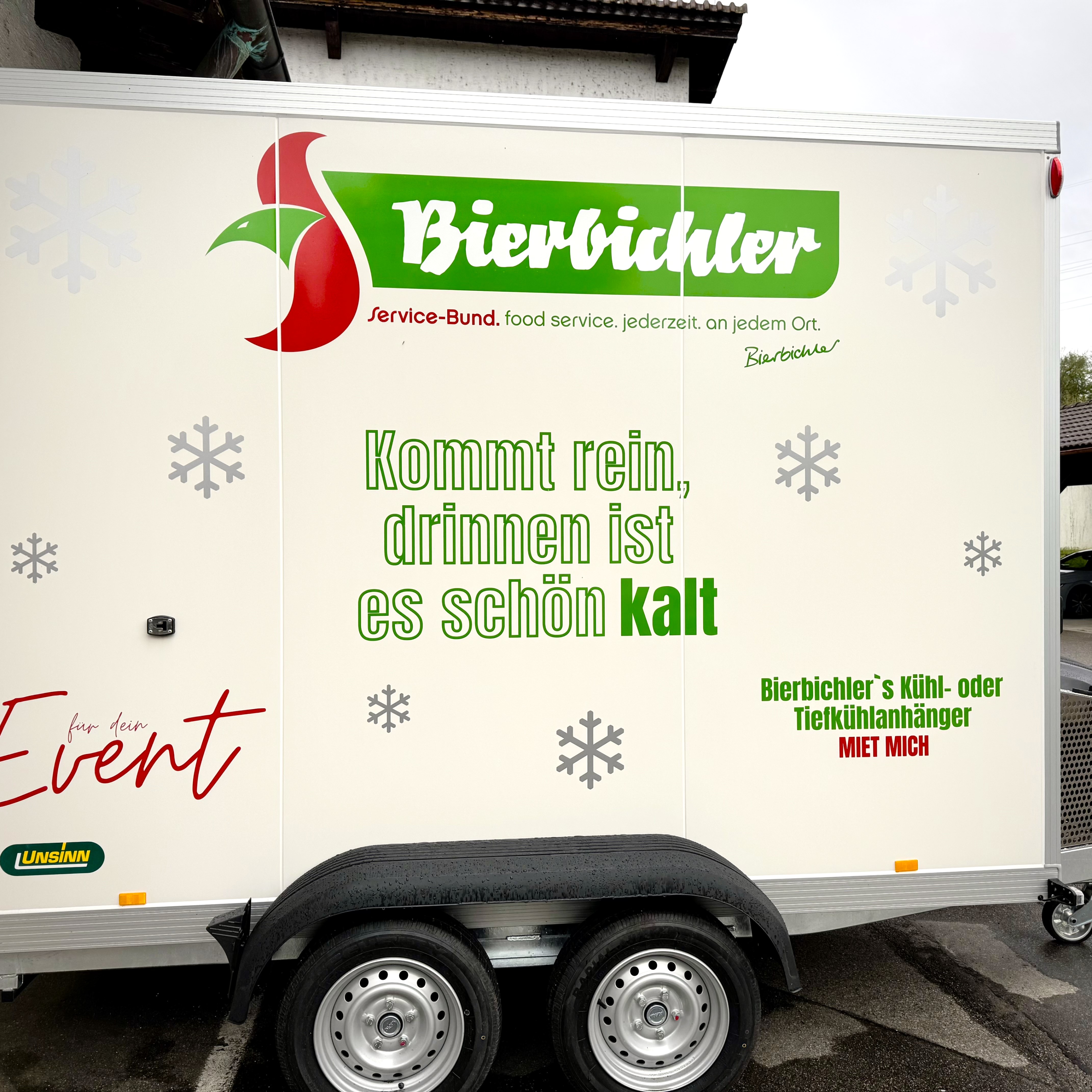 Ja wo gibt es denn sowas?! Beim Bierbichler - ein TK Kühlanhänger für Ihren Event, Grossveranstaltung oder Firmenfeier. Reservieren Sie sich jetzt schon den Anhänger für Ihren Event! weisser TK Kühlanhänger mit grüner Aufschrift von Bierbichler für Feste & Festlichkeiten